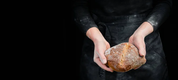 Fragrant ciabatta in women\'s hands, food photography recipe idea. Black baking background.