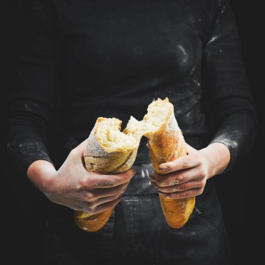 Kadınların elleri baget ekmeğini kırıyor. Siyah arkaplanda izole.