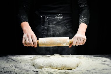 Merdaneli kadın elleri hamuru ekmek ya da pizza için hazırlar. Siyah aşçılık arka planı.