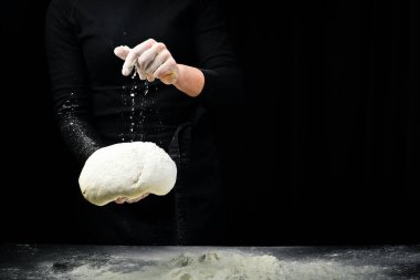 Ellerindeki buğday unundan taze hamur. Karanlık bir arka planda. Aşçılık arkaplanı.