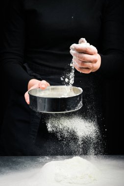 Elektiriğe un atmak. Un ellerinde. Karanlık bir arka planda.