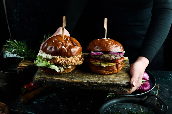 요리사가 널빤지 맛있는 햄버거 어두운 배경에서 — 스톡 사진