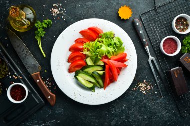 Tabakta çeşitli sebzeler. Taze sebze dilimleme: salatalık, domates, biber. Restoran menüsü. Üst görünüm.