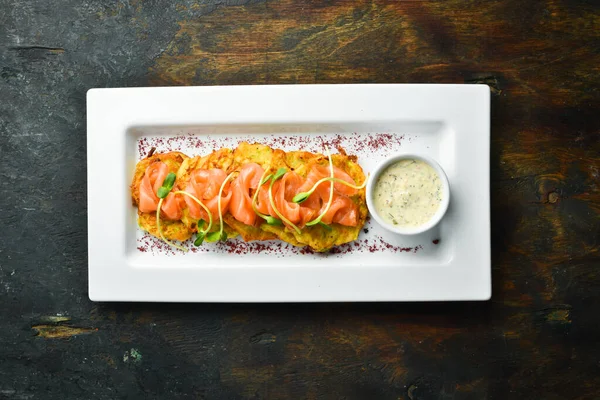 Potato pancakes with salmon and sauce on a white plate. Top view.