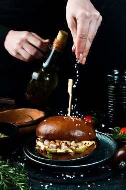 Şefin ellerinde sulu burger. Pastırmalı hamburger, turşu ve peynir soslu. Fast food konsepti.