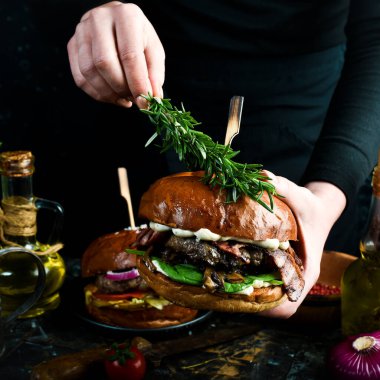 Pastırma ve sebzeli leziz ızgara hamburger. Karanlık bir arka planda. Fast food konsepti.