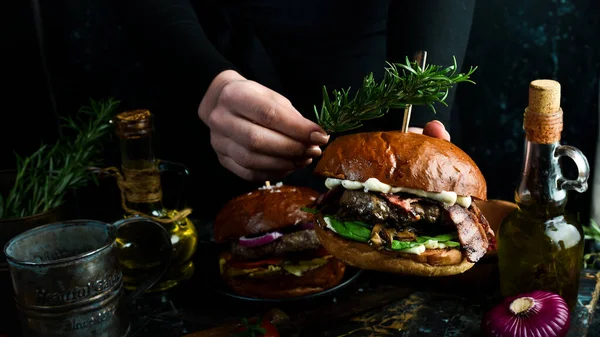 Delicious grilled hamburger with bacon and vegetables. On a dark background. Fast food concept.