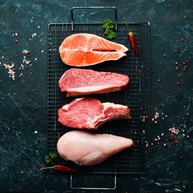 Çiğ yemek, somonlu biftek, dana eti, sığır eti ve tavuk, koyu taşlı arka planda. Üst Manzara. Organik yiyecekler.