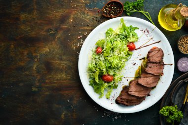 Salata ve sebzeli dana biftek. Siyah bir arka planda. Üst Manzara. Kırsal biçim.