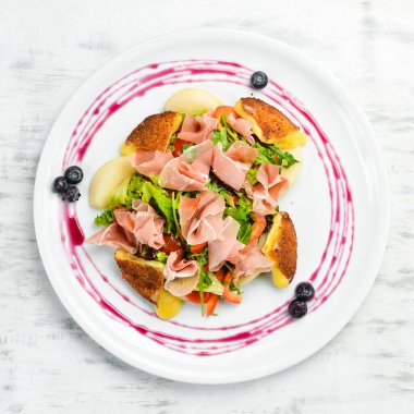 Prosciutto salatası, peynir ve sebzeler beyaz tabakta. Üst Manzara. Kırsal biçim.