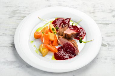 Kereviz kökü ve beyaz tabakta sebzeli fırında ördek göğsü. Üst Manzara. Kırsal biçim.