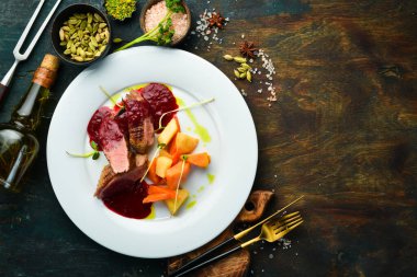 Kereviz kökü ve beyaz tabakta sebzeli fırında ördek göğsü. Üst Manzara. Kırsal biçim.