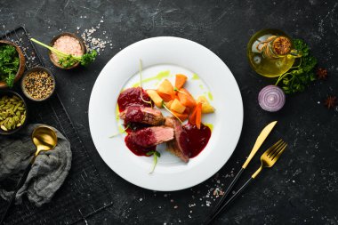 Kereviz kökü ve beyaz tabakta sebzeli fırında ördek göğsü. Üst Manzara. Kırsal biçim.