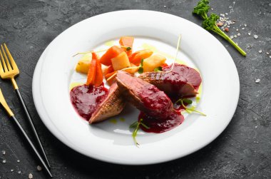 Kereviz kökü ve beyaz tabakta sebzeli fırında ördek göğsü. Üst Manzara. Kırsal biçim.