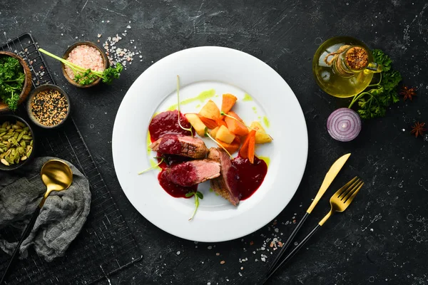 Kereviz kökü ve beyaz tabakta sebzeli fırında ördek göğsü. Üst Manzara. Kırsal biçim.