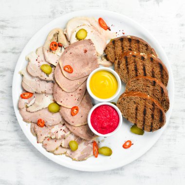 Dilimlenmiş et ve soslu beyaz tabakta salam. Üst görünüm.