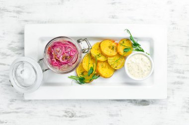 Soğanlı ve kızarmış patatesli ringa balığı. Soğuk atıştırmalıklar. Beyaz bir tabakta. Üst görünüm.