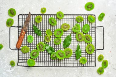 Kurutulmuş meyve. Tahtada şekerli kivi var. Taş bir arka planda.
