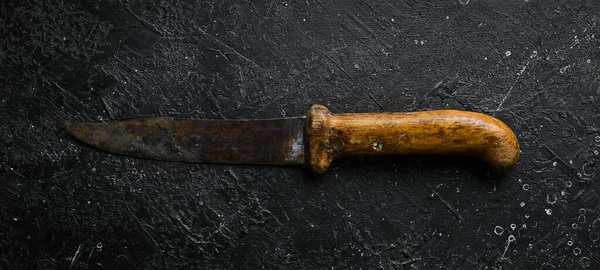 Old kitchen knife with wooden handle. Kitchen metal knife. Top view. On a stone background.