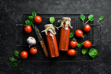 Şişede Bloody Mary kokteyli. İki şişe domates suyu. Kiraz domatesleri. Üst Manzara. Taş bir arka planda.