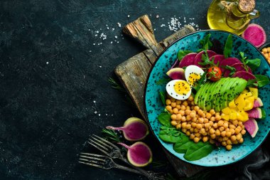 Dengeli yiyecek: nohut, avokado, yumurta, karpuz turpu ve ıspanak. Buda kasesi taş zeminde lezzetli yemek konsepti.