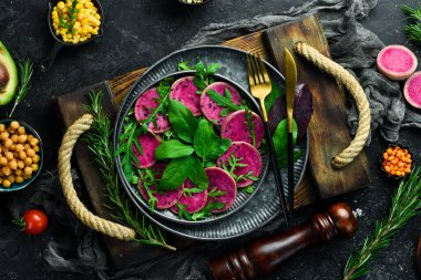 Taze sağlıklı salata: ıspanak, turp karpuzu, siyah susam ve zeytinyağı. Sağlıklı yiyecekler. Üst Manzara. Taş bir arka planda.