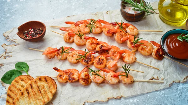 Shrimp for barbecue. Grilled shrimps on skewers with lemon and garlic. Seafood. On a stone background.