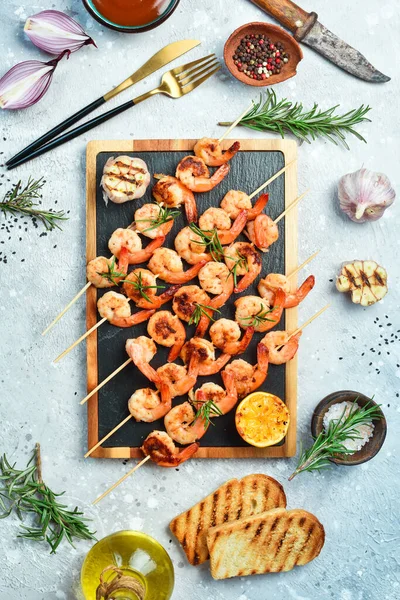 Shrimp for barbecue. Grilled shrimps on skewers with lemon and garlic. Seafood. On a stone background.