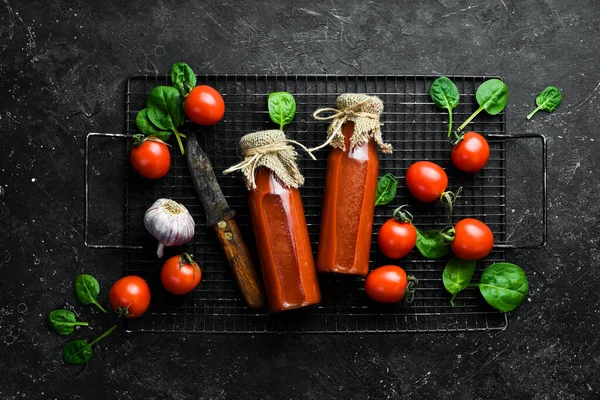 Şişede Bloody Mary kokteyli. İki şişe domates suyu. Kiraz domatesleri. Üst Manzara. Taş bir arka planda.