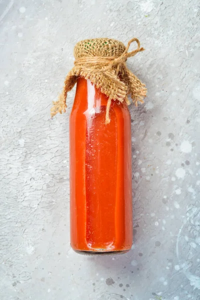 Cam Şişede Ev Yapımı Domates Suyu. Üst Manzara. Taş bir arka planda.