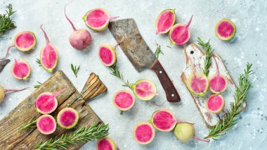 Mutfak tahtasında dilimlenmiş turp karpuzu. Beslenme amaçlı sebzeler. Gri taştan bir arka planda.