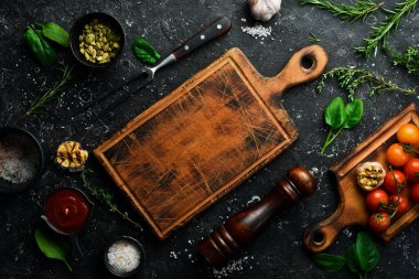 Siyah taş pişirme üzerine mutfak tahtası. Taş bir masada taze sebze ve baharatlar. Üst görünüm.