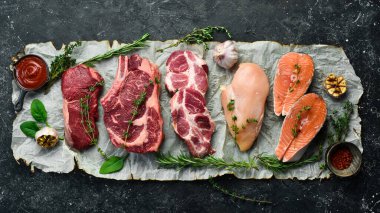 Et seti. Balık biftek, dana biftek ve tavuk göğsü. Üst Manzara. Siyah taştan bir arka planda.