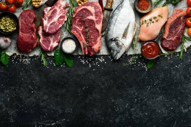 Çeşitli protein kaynakları konsepti - kaburga, dorado, domuz eti, yumurta. Üst Manzara. Siyah taştan bir arka planda.