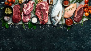 Çeşitli protein kaynakları konsepti - kaburga, dorado, domuz eti, yumurta. Üst Manzara. Siyah taştan bir arka planda.