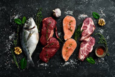 Farklı et setleri: balık, sığır eti ve domuz eti. Vücut için hayvansal protein kaynağı. Siyah taştan bir arka planda.