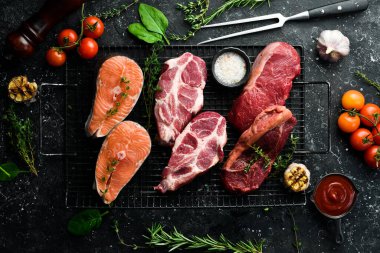 Farklı et setleri: balık, sığır eti ve domuz eti. Vücut için hayvansal protein kaynağı. Siyah taştan bir arka planda.
