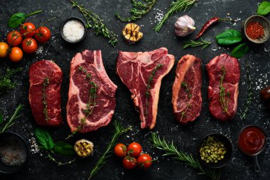 Baharatlı ızgara için çeşitli çiğ biftekler, biftek, biftek, pirzola. Üst Manzara. Siyah taştan bir arka planda.