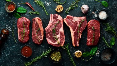 Baharatlı ızgara için çeşitli çiğ biftekler, biftek, biftek, pirzola. Üst Manzara. Siyah taştan bir arka planda.