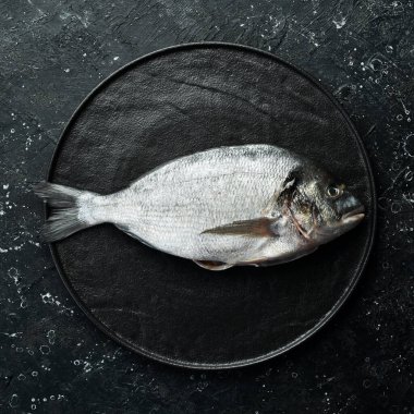 Siyah taş tabakta Dorado balığı. Deniz ürünleri. Üst Manzara. Siyah taştan bir arka planda.