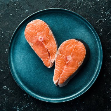 Balık. Çiğ somon ya da tabakta alabalık bifteği. Üst Manzara. Siyah taştan bir arka planda.
