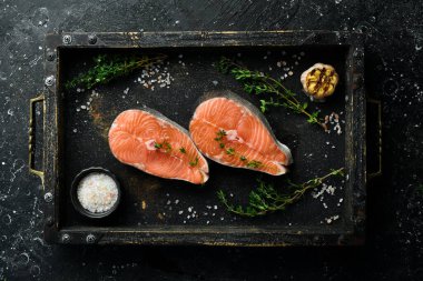 Somon bifteği ya da baharatlı alabalık pişirmeye hazır. Üst Manzara. Siyah taştan bir arka planda.