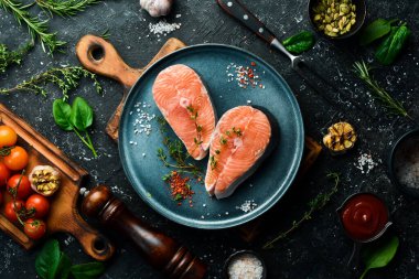 Somon bifteği ya da baharatlı alabalık pişirmeye hazır. Üst Manzara. Siyah taştan bir arka planda.