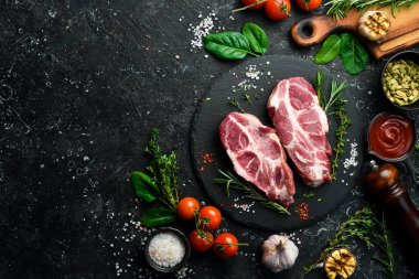 Taze domuz eti. İki domuz bifteği. Üst Manzara. Siyah taştan bir arka planda.