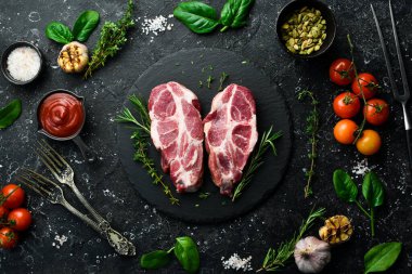 Baharatlı ve otlu çiğ domuz bifteği. Üst Manzara. Siyah taştan bir arka planda.