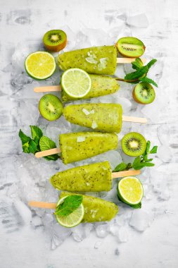 Ev yapımı buzlu kivi, limon ve nane. Tahta arka planda meyveli şerbet. Üst Manzara. Beyaz bir arkaplanda.