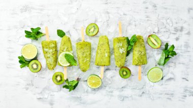 Ev yapımı buzlu kivi, limon ve nane. Tahta arka planda meyveli şerbet. Üst Manzara. Beyaz bir arkaplanda.