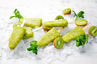 Ev yapımı buzlu kivi, limon ve nane. Tahta arka planda meyveli şerbet. Üst Manzara. Beyaz bir arkaplanda.