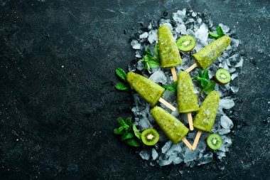 Buzlu ve kivili buzlu buzlu dondurma. Siyah taştan bir arka planda.