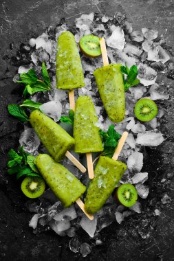 Buzlu ve kivili buzlu buzlu dondurma. Siyah taştan bir arka planda.